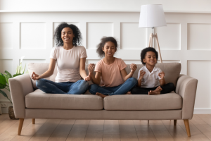 mother with two children sitting on the couch practicing mindfulness meditation